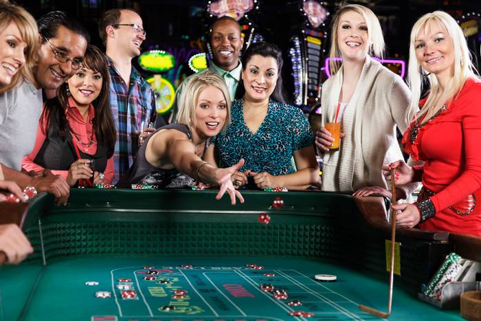 A diverse group of people playing at a craps table inside a casino.